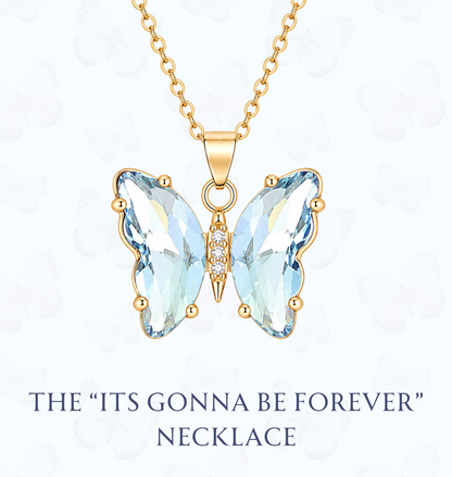 Gold butterfly pendant necklace with light blue faceted crystal wings and a small center accent, shown on a white background with the text 'THE "ITS GONNA BE FOREVER" NECKLACE' and the website 'www.hebejewel.
