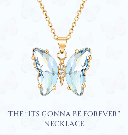 Gold butterfly pendant necklace with light blue faceted crystal wings and a small center accent, shown on a white background with the text 'THE "ITS GONNA BE FOREVER" NECKLACE' and the website 'www.hebejewel.