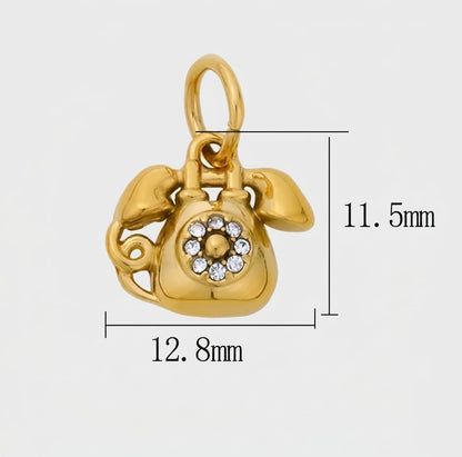 A gold charm shaped like a rotary telephone, shown on a light gray background with dimension lines and measurements indicating 12.8mm width, 11.