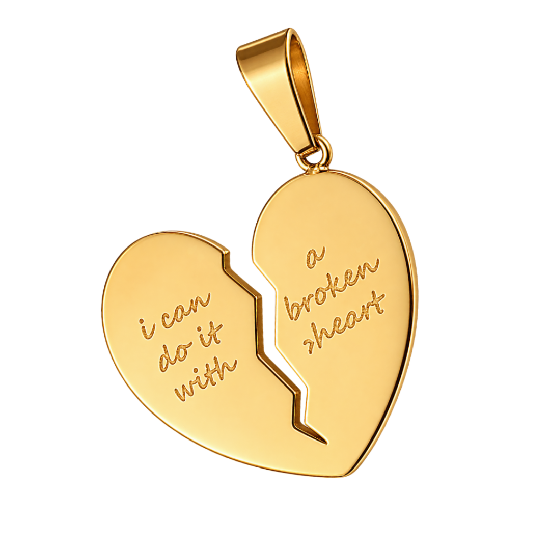 A gold heart-shaped pendant broken in two pieces, with engraved text reading 'i can do it with' on the left half and 'a broken heart' on the right half, shown on a white background with a green 'NEW ARRIVAL' banner in the top-left corner.