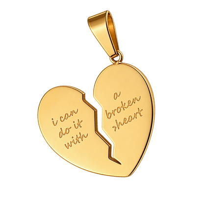 A gold heart-shaped pendant broken in two pieces, with engraved text reading 'i can do it with' on the left half and 'a broken heart' on the right half, shown on a white background with a green 'NEW ARRIVAL' banner in the top-left corner.